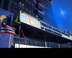 Foto da fachada principal do prédio-sede do TRT-16 iluminada na cor azul. À esquerda, estão hasteadas as bandeiras do Brasil, Maranhão e do TRT-16 .