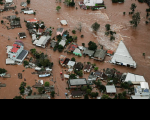 Foto aérea de casas inundadas pela enchente na região do Vale do Taquari, no Rio Grande do Sul. Na imagem também há várias árvores.