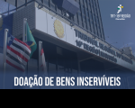Fachada do prédio-sede do TRT16 com bandeiras hasteadas do Brasil, do Maranhão e do Tribunal. Abaixo, texto Doação de Bens Inservíveis na cor branca. No canto superior à direita, logomarca do Tribunal na cor branca.