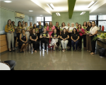 Foto de pessoas em pé e outras sentadas, segurando arranjos florais amarelos, sorrindo e posando para a foto.