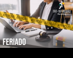 Foto de um homem vestindo terno escuro e camisa social branca, digitando em um notebook que está sobre uma mesa. À frente, faixa na cores amarelo e preto, com a inscrição ATENÇÃO em preto, atravessa a foto da esquerda para a direita. No canto superior direito, logo do TRT-16 na versão branca. No canto inferior esquerdo, texto FERIADO na cor branca. 