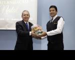Dois homens posando para foto, onde o da esquerda entrega a cesta básica de alimentação para o da direita.