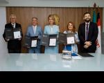 cinco pessoas posando para foto. Quatro delas seguram um papel com os selos obliterados. 