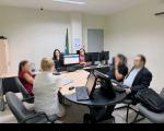 Seis pessoas reunidas em uma sala, envolta de uma mesa, em uma audiência de ocnciliação.