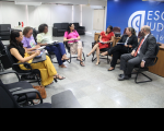 Foto mostra um reunião de pessoas. Todas estão sentados na cadeiras posicionadas em formato de meia lua no centro do auditório da Escola judicial do TRT-16