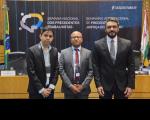 Arte feita com a foto de três homens, vestidos com terno. Eles estão em pé, posicionados em frente a um painel que tem informações sobre o Seminário Internacional de Precedentes Trabalhistas