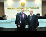 Foto de dois homens usando togas na cor preta. Ao fundo, em uma parede branca o nome TRIBUNAL REGIONAL DO TRABALHO - 16ª Região
