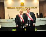 Foto mostra dois homens, em pé, ambos estão usando togas. Ao fundo o nome do Tribunal Regional do Trabalho da 16ª Região