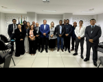 Foto mostra um grupo de pessoas, todos reunidos em um auditório
