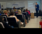 Foto mostra um homem realizando uma palestra em um auditório. Muitas pessoas estão sentadas.