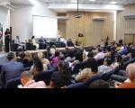 Foto de auditório com plateia e autoridades no palco.