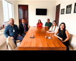 Foto mostra seis pessoas sentados à mesa. São 3 homens e três mulheres