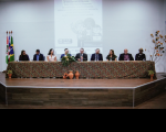 Foto de mesa de honra em evento com nove pessoas.