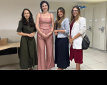 Foto mostra 4 mulheres uma ao lado da outra. Todas estão em pé e dentro de uma sala