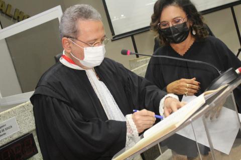 Homem de toga apoiado em uma tribuna assinando o ato de  posse