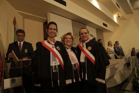 duas mulheres e um homem vestidos de toga em pé pousando para foto 