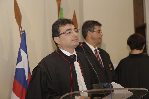 homem de toga em frente a uma tribuna discursando
