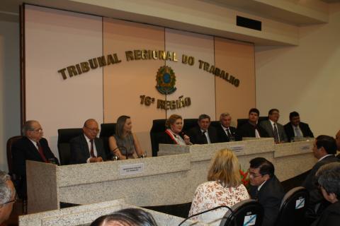 pessoas sentadas em frente a uma mesa de honra com várias autoridades